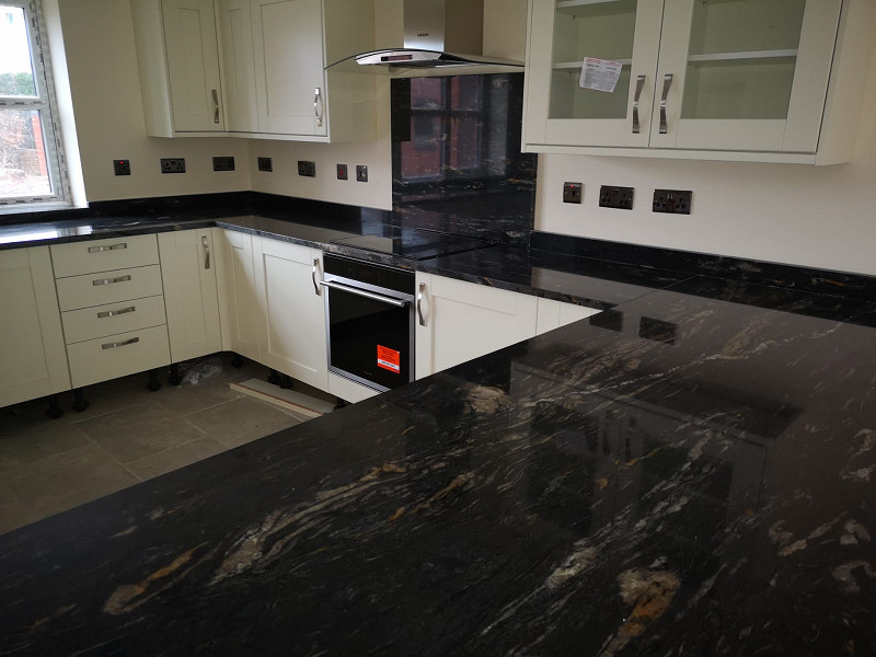 Lantlig inredning av ett svart svart kök, med granitbänkskiva