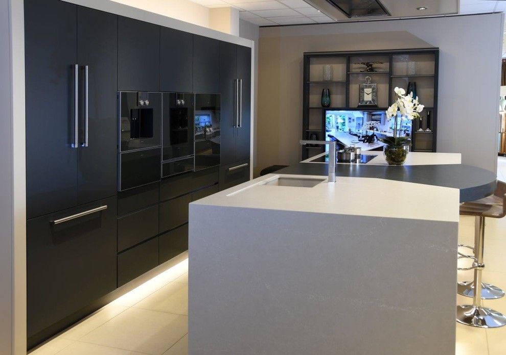 Large modern single-wall open plan kitchen in Other with a belfast sink, flat-panel cabinets, grey cabinets, soapstone worktops, integrated appliances, an island and grey worktops.