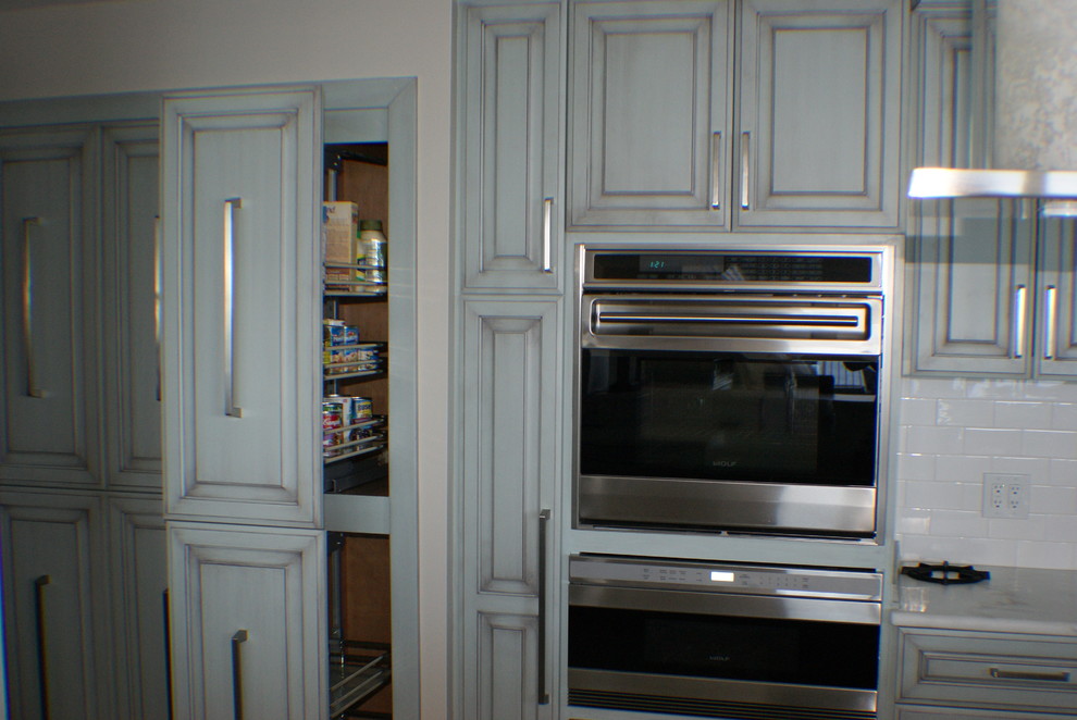 Example of a tuscan galley eat-in kitchen design in Jacksonville with raised-panel cabinets, green cabinets, marble countertops, white backsplash, ceramic backsplash and stainless steel appliances