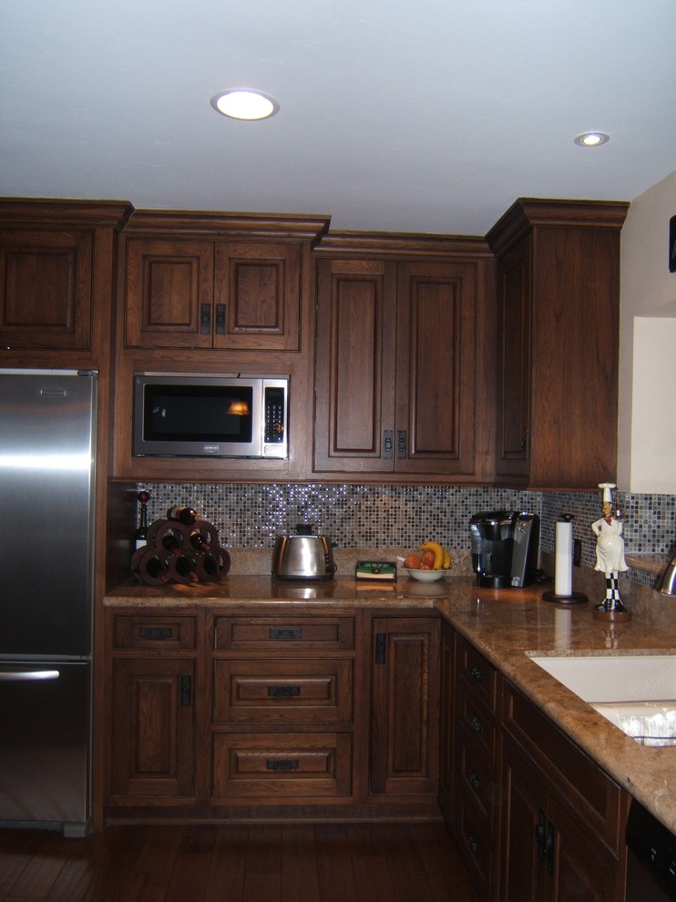 Cette image montre une cuisine méditerranéenne en bois brun avec un placard avec porte à panneau surélevé et un plan de travail en granite.