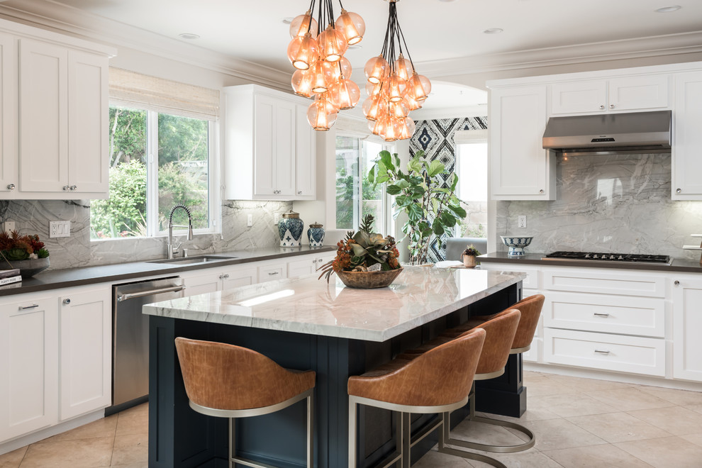 Photo of a beach style kitchen in Orange County with a submerged sink, shaker cabinets, white cabinets, grey splashback, stainless steel appliances, an island, beige floors and grey worktops.