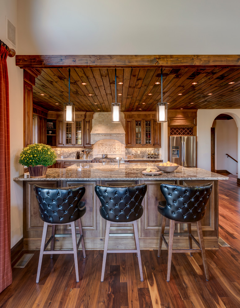 Modern inredning av ett stort u-kök, med luckor med glaspanel, skåp i mellenmörkt trä, granitbänkskiva, beige stänkskydd, rostfria vitvaror, mörkt trägolv, en köksö och brunt golv