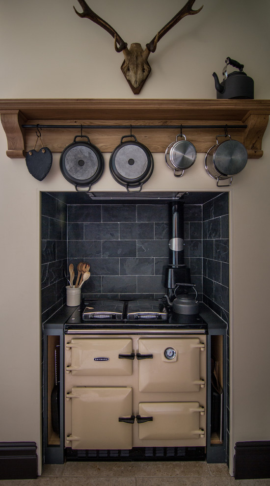Bild på ett litet funkis kök, med skåp i shakerstil, träbänkskiva, svart stänkskydd, stänkskydd i stenkakel, färgglada vitvaror, kalkstensgolv, en nedsänkt diskho och gröna skåp