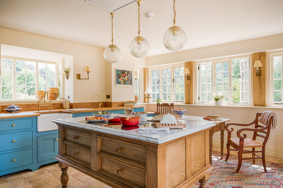 Inspiration for a medium sized rural l-shaped enclosed kitchen in Gloucestershire with a belfast sink, shaker cabinets, blue cabinets, wood worktops, brown splashback, wood splashback, integrated appliances, terracotta flooring, an island, beige floors and brown worktops.