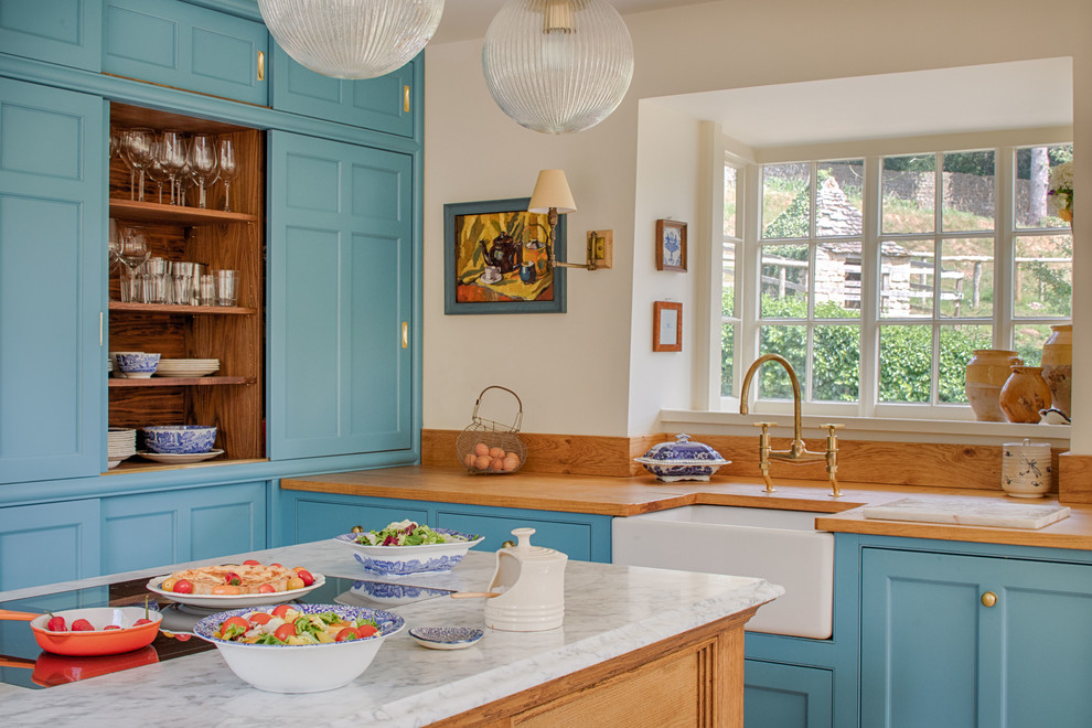 Foto på ett brun kök, med skåp i shakerstil, en köksö, en rustik diskho, blå skåp, träbänkskiva, integrerade vitvaror och klinkergolv i terrakotta