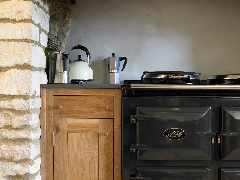 Mittelgroße Country Wohnküche ohne Insel in L-Form mit Landhausspüle, flächenbündigen Schrankfronten, hellbraunen Holzschränken, bunten Elektrogeräten und Kalkstein in Gloucestershire