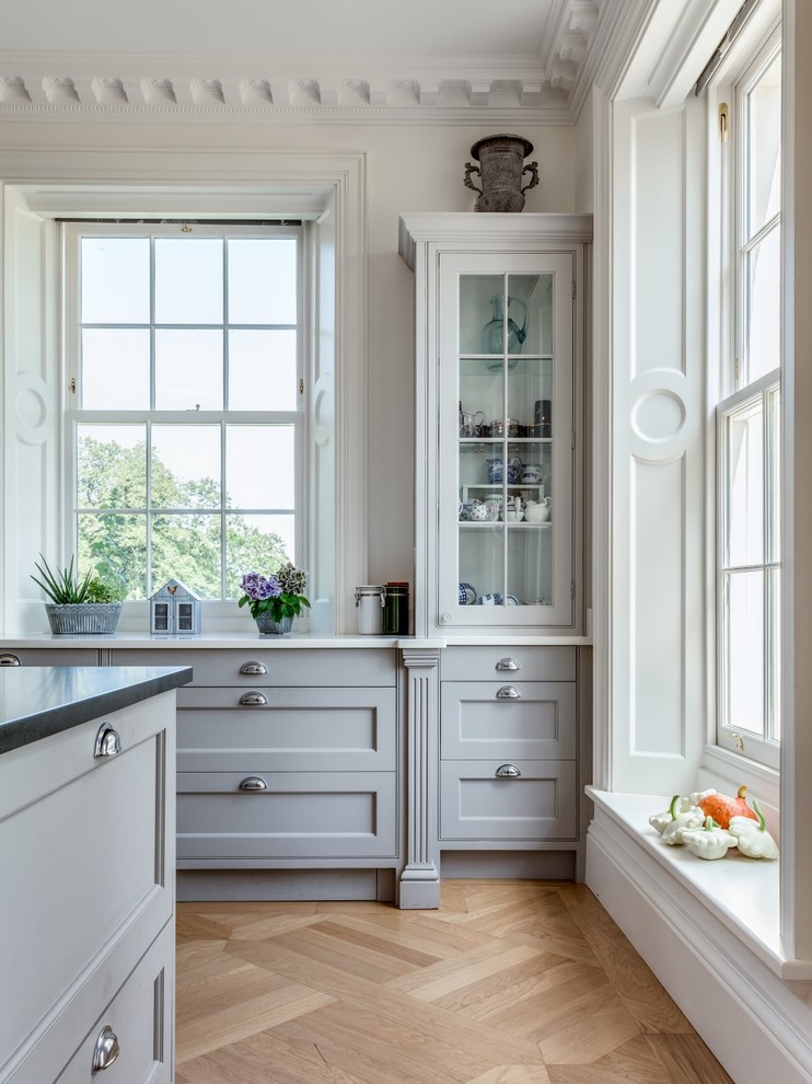 Imagen de cocina contemporánea con armarios estilo shaker, electrodomésticos de acero inoxidable, suelo de madera clara y una isla