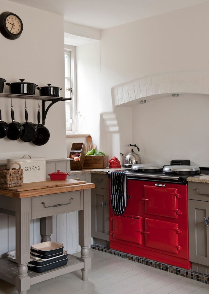 Example of a mid-sized farmhouse l-shaped light wood floor eat-in kitchen design in London with a farmhouse sink, flat-panel cabinets, medium tone wood cabinets, wood countertops, white backsplash, colored appliances and no island