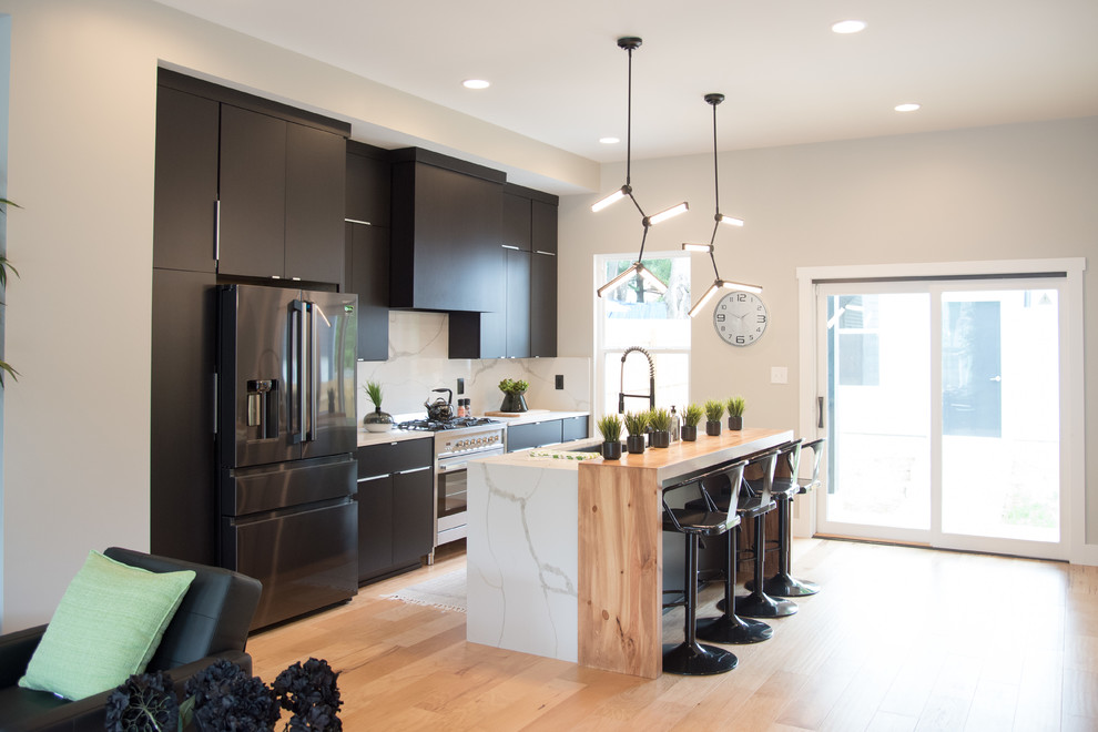 Contemporary galley kitchen in Indianapolis with flat-panel cabinets, brown cabinets, white splashback, stainless steel appliances, light hardwood flooring, an island, brown floors, marble worktops, marble splashback and white worktops.