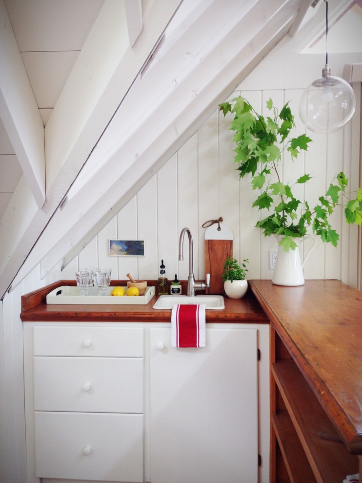 Foto di una piccola cucina stile rurale con lavello da incasso, ante lisce, ante bianche, top in legno, paraspruzzi bianco e pavimento in legno massello medio