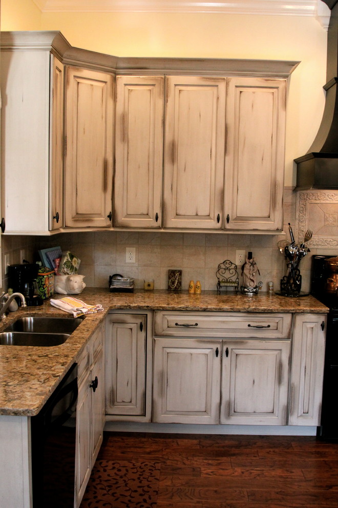 Foto di una grande cucina country con lavello sottopiano, ante con bugna sagomata, ante con finitura invecchiata, top in quarzo composito, paraspruzzi beige, paraspruzzi in gres porcellanato, elettrodomestici neri e parquet scuro