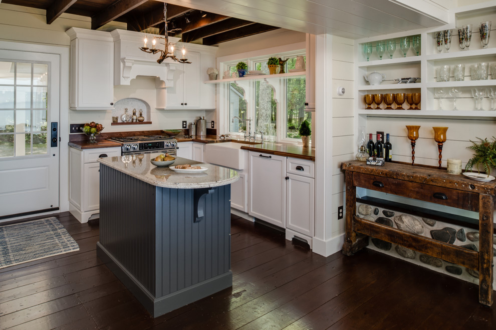 Example of a small mountain style l-shaped dark wood floor and brown floor enclosed kitchen design in Grand Rapids with a farmhouse sink, wood countertops, white cabinets, recessed-panel cabinets, stainless steel appliances, white backsplash, wood backsplash and an island