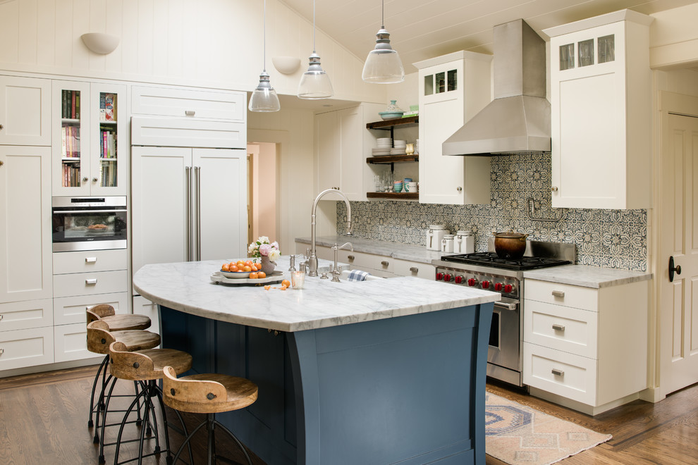 Inspiration for a large traditional l-shaped kitchen/diner in San Francisco with a belfast sink, recessed-panel cabinets, white cabinets, marble worktops, grey splashback, cement tile splashback, integrated appliances, medium hardwood flooring, multiple islands and brown floors.