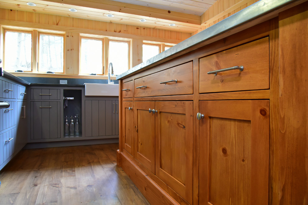 Inspiration for a medium sized country l-shaped open plan kitchen in Boston with a belfast sink, flat-panel cabinets, blue cabinets, granite worktops, grey splashback, stone slab splashback, stainless steel appliances, medium hardwood flooring, an island, brown floors and grey worktops.