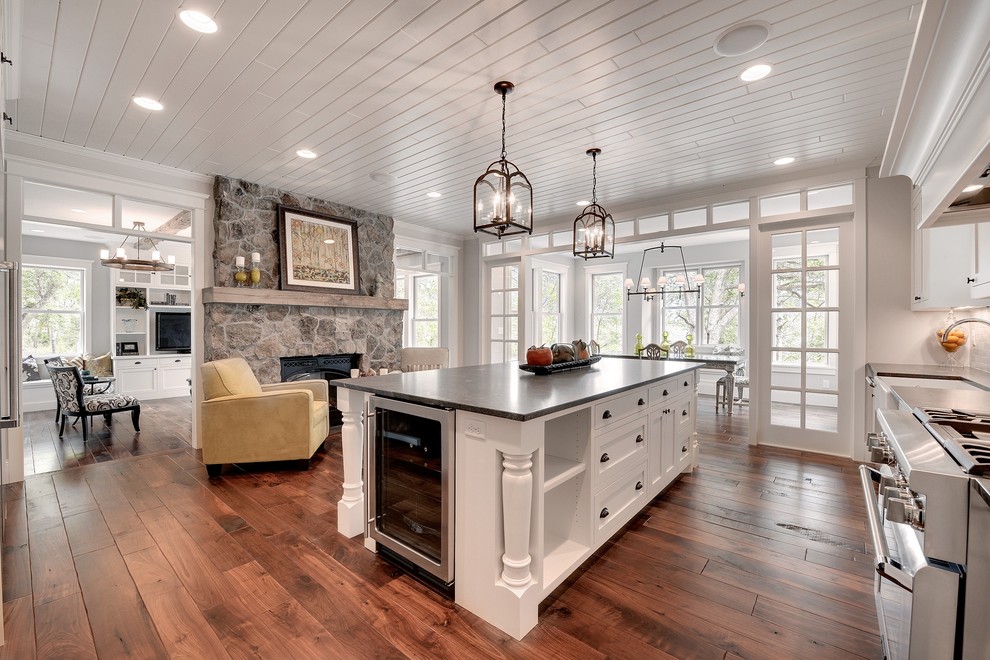 Large transitional l-shaped dark wood floor and brown floor enclosed kitchen photo in Minneapolis with a farmhouse sink, white cabinets, stainless steel appliances, soapstone countertops, an island and shaker cabinets