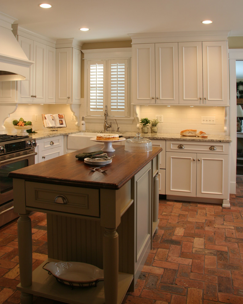 Idéer för ett mellanstort amerikanskt kök, med en rustik diskho, släta luckor, vita skåp, granitbänkskiva, vitt stänkskydd, stänkskydd i keramik, integrerade vitvaror, tegelgolv och en köksö