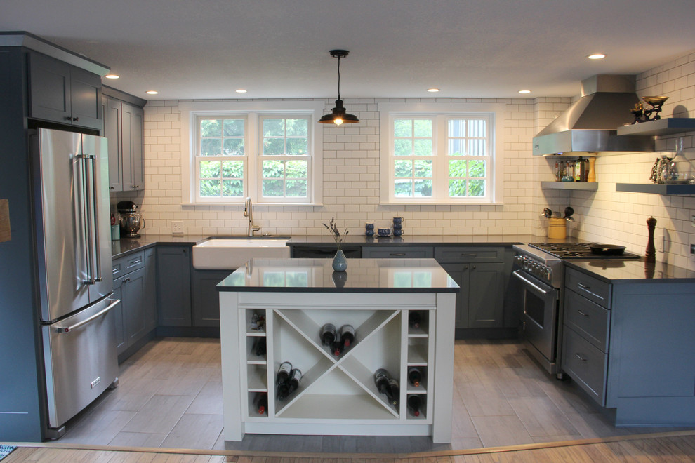 Foto på ett litet amerikanskt kök, med en rustik diskho, skåp i shakerstil, blå skåp, bänkskiva i kvarts, vitt stänkskydd, stänkskydd i tunnelbanekakel, rostfria vitvaror, klinkergolv i keramik, en köksö och brunt golv