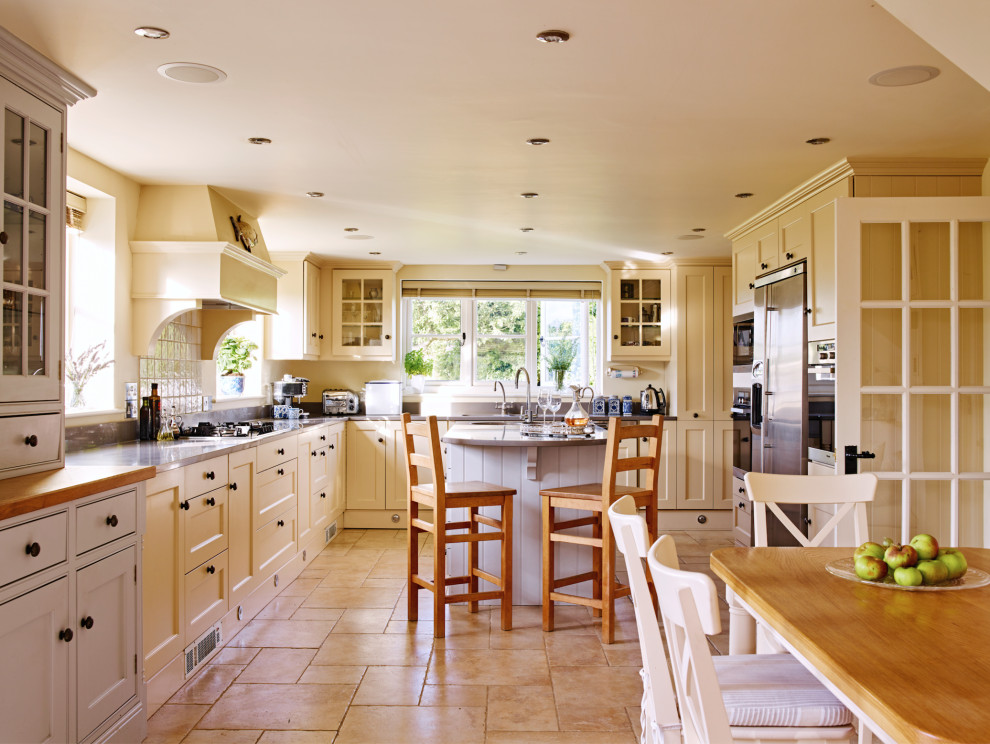 This is an example of a rural l-shaped kitchen in Hampshire with a submerged sink, recessed-panel cabinets, beige cabinets, stainless steel appliances, an island, beige floors and grey worktops.