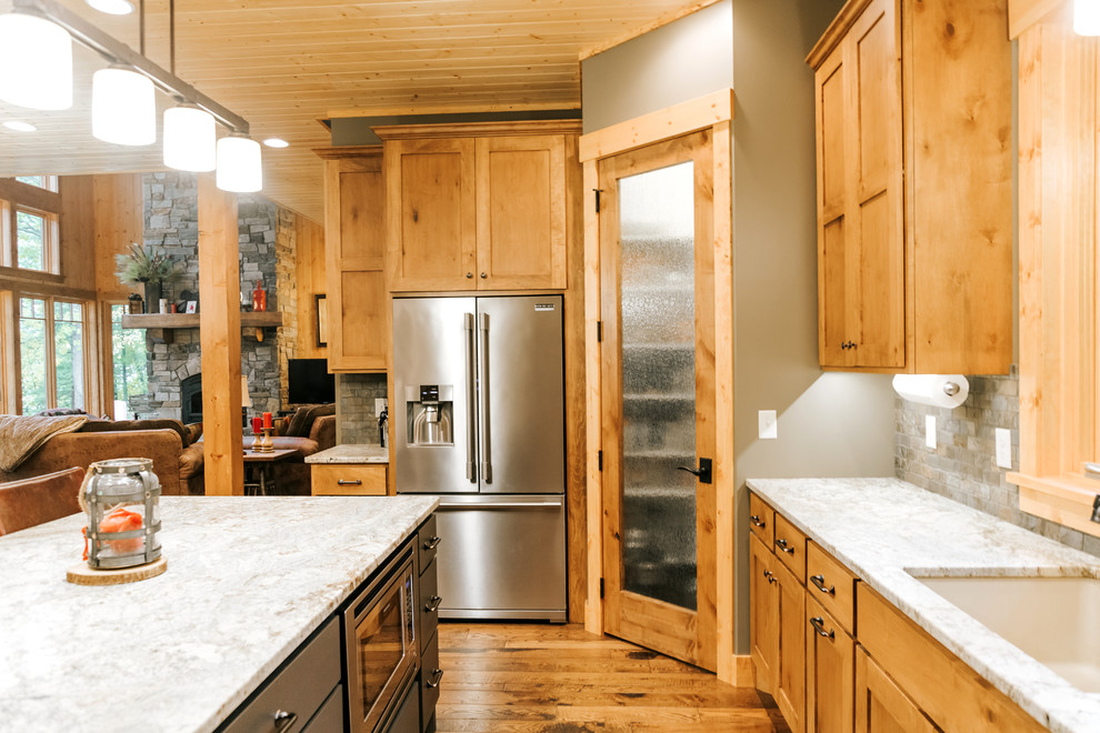 Mountain style u-shaped medium tone wood floor and brown floor open concept kitchen photo in Minneapolis with an undermount sink, shaker cabinets, medium tone wood cabinets, gray backsplash, stainless steel appliances and an island