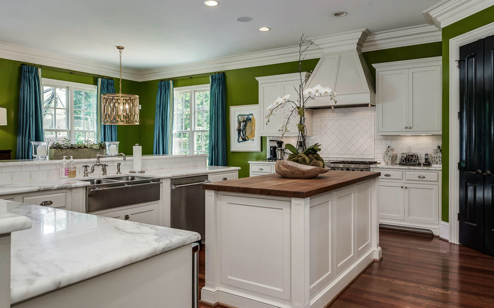 Elegant u-shaped dark wood floor kitchen photo in Charlotte with a farmhouse sink, recessed-panel cabinets, white cabinets, white backsplash, subway tile backsplash, stainless steel appliances and an island