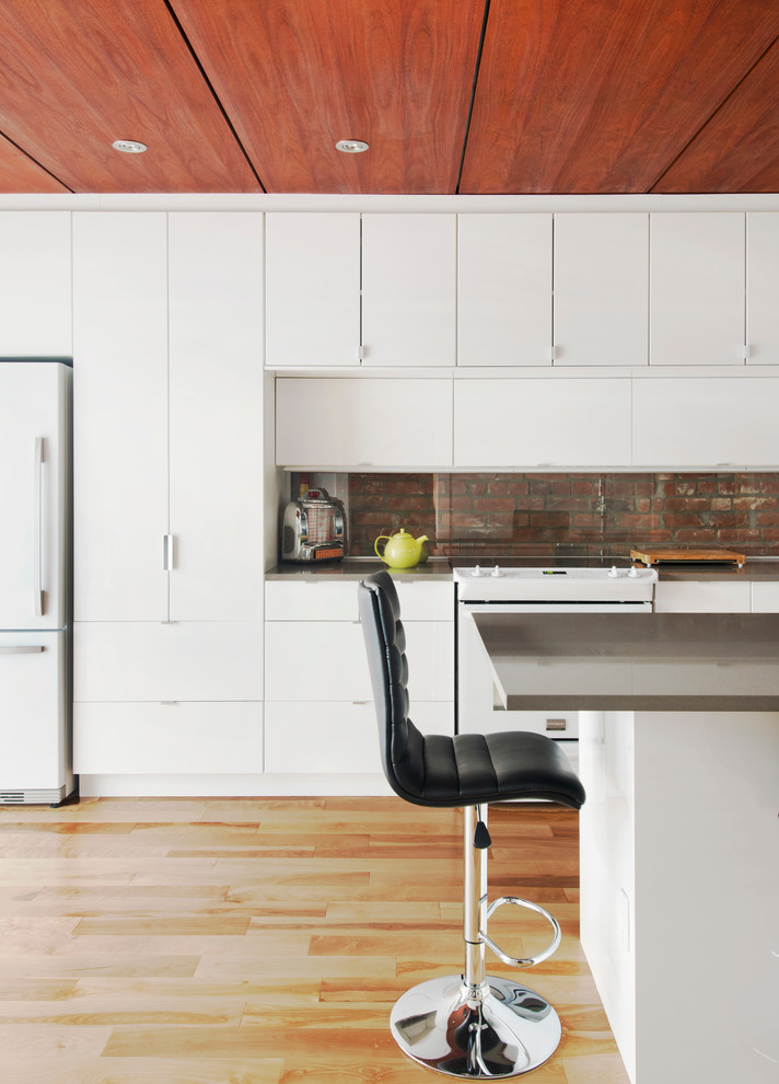 Modelo de cocina contemporánea abierta con armarios con paneles lisos, puertas de armario blancas, salpicadero de vidrio templado y electrodomésticos blancos