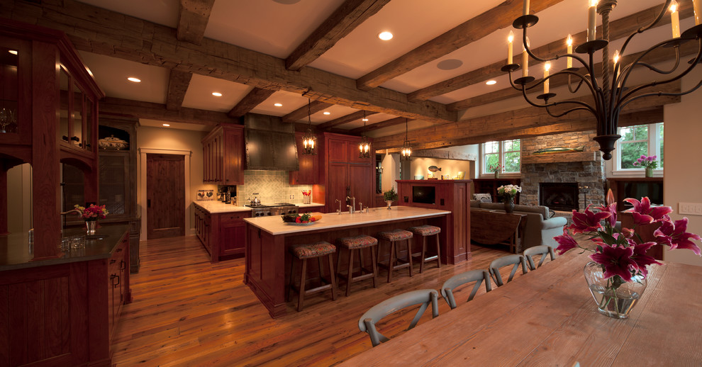 На фото: кухня в стиле рустика с фасадами с утопленной филенкой, темными деревянными фасадами, серым фартуком и техникой под мебельный фасад