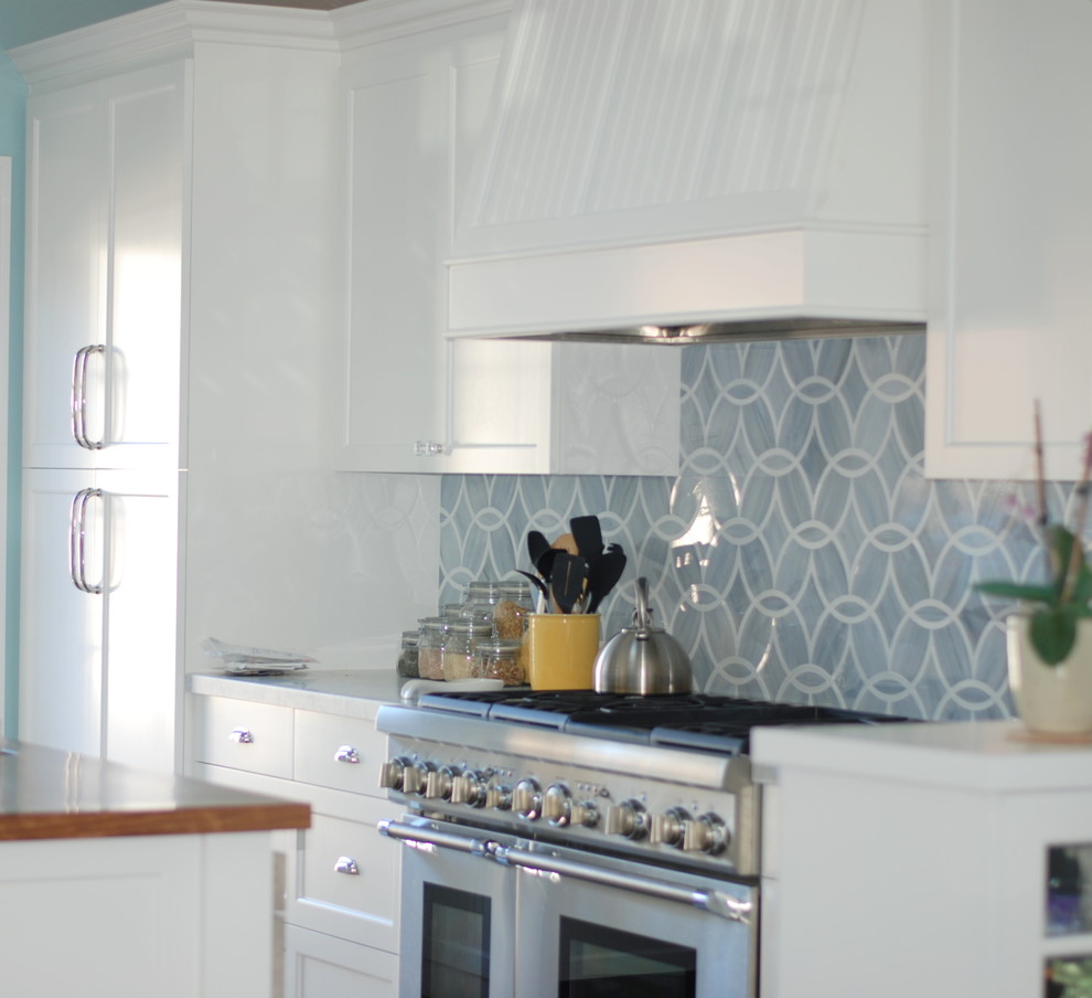 Foto på ett mellanstort maritimt kök, med en rustik diskho, skåp i shakerstil, vita skåp, marmorbänkskiva, grått stänkskydd, glaspanel som stänkskydd, rostfria vitvaror, mörkt trägolv och en köksö