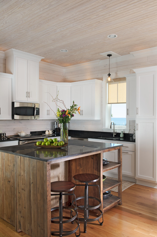 Immagine di una cucina costiera con lavello sottopiano, ante in stile shaker, elettrodomestici in acciaio inossidabile e pavimento in legno massello medio