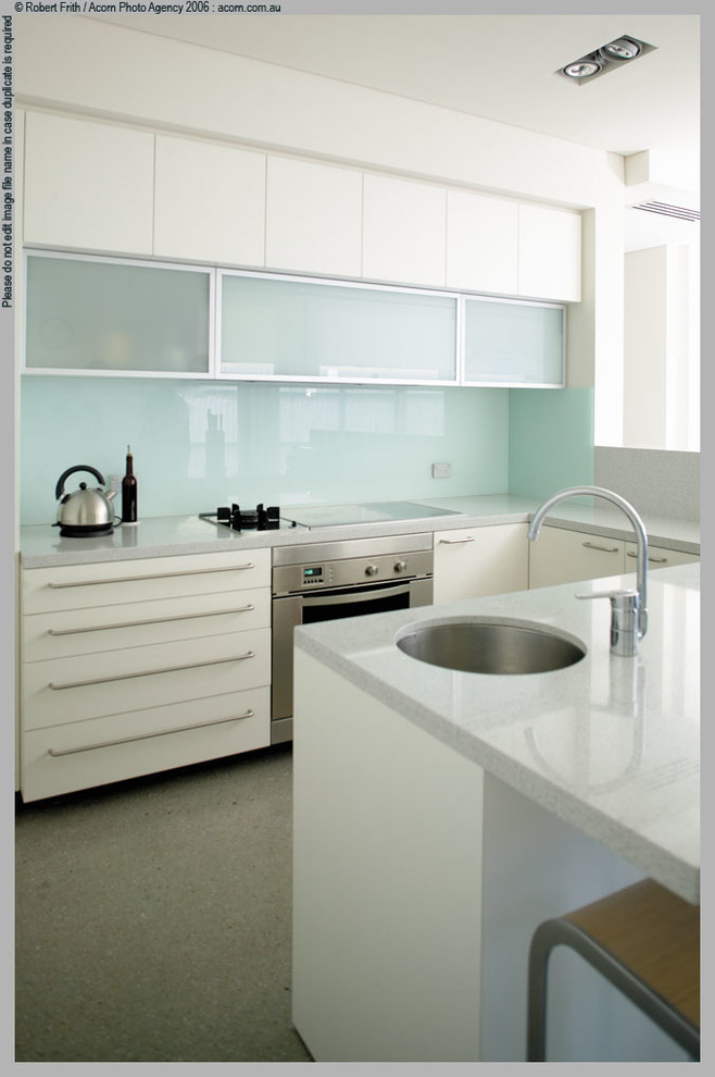 Small contemporary galley kitchen/diner in Perth with a submerged sink, flat-panel cabinets, white cabinets, engineered stone countertops, glass sheet splashback, stainless steel appliances and concrete flooring.