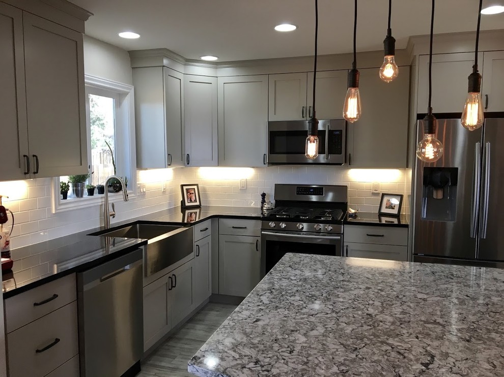 Mid-sized cottage l-shaped vinyl floor and gray floor enclosed kitchen photo in Denver with a farmhouse sink, shaker cabinets, beige cabinets, quartz countertops, white backsplash, stainless steel appliances, an island and subway tile backsplash