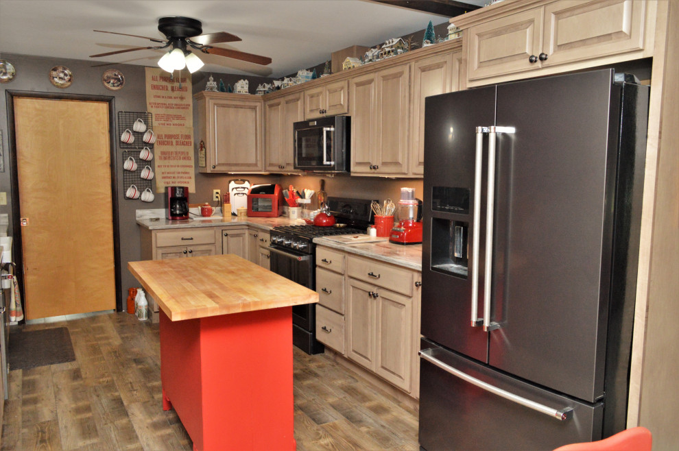 Foto på ett mellanstort lantligt brun kök, med en rustik diskho, luckor med upphöjd panel, beige skåp, bänkskiva i kvartsit, svarta vitvaror, laminatgolv, en köksö och brunt golv