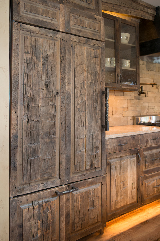 Inspiration for a large rustic l-shaped medium tone wood floor and brown floor eat-in kitchen remodel in Other with shaker cabinets, distressed cabinets, limestone countertops, brown backsplash, stone tile backsplash, colored appliances and an island