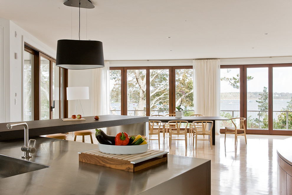 Modern inredning av ett kök och matrum, med en integrerad diskho, bänkskiva i rostfritt stål, rostfria vitvaror, ljust trägolv och en halv köksö