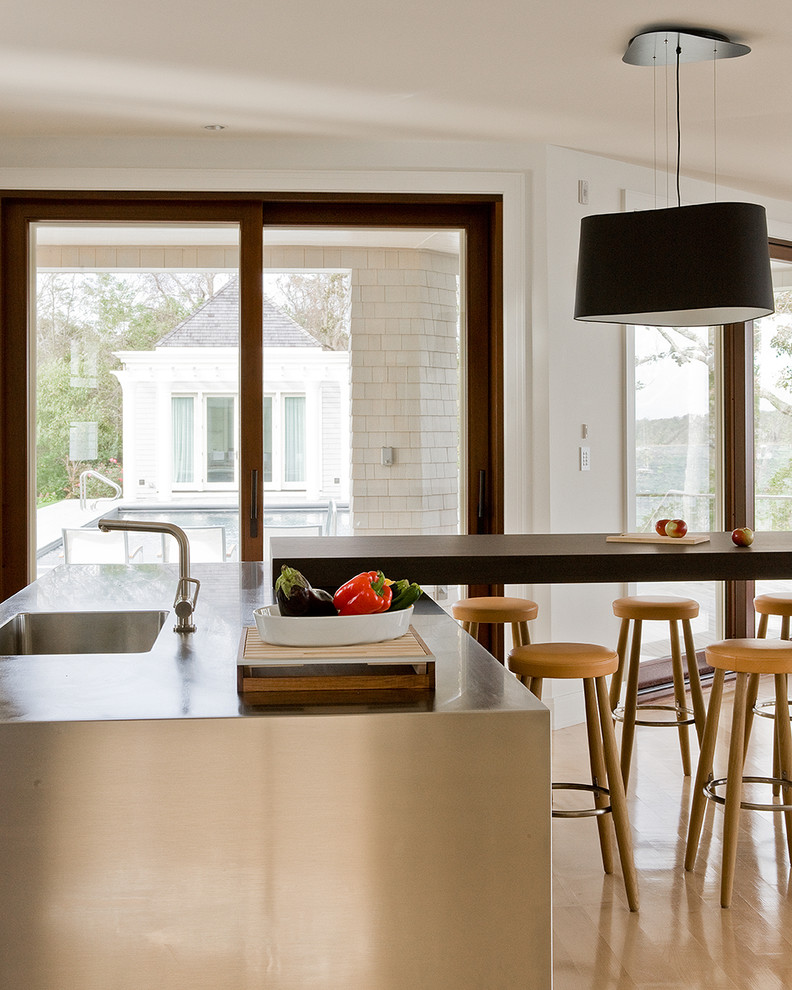 На фото: кухня в современном стиле с обеденным столом, монолитной мойкой, столешницей из нержавеющей стали и светлым паркетным полом с