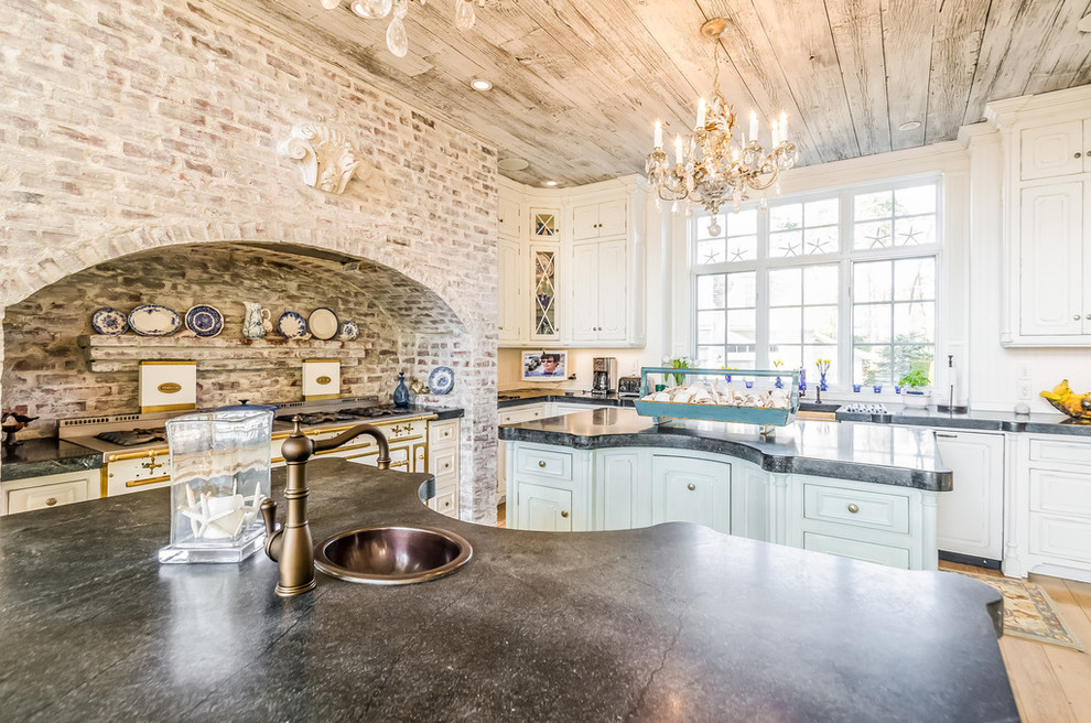 Foto de cocina romántica de tamaño medio con fregadero sobremueble, armarios con paneles empotrados, suelo de madera en tonos medios, dos o más islas, puertas de armario blancas, encimera de cemento, suelo marrón y encimeras negras