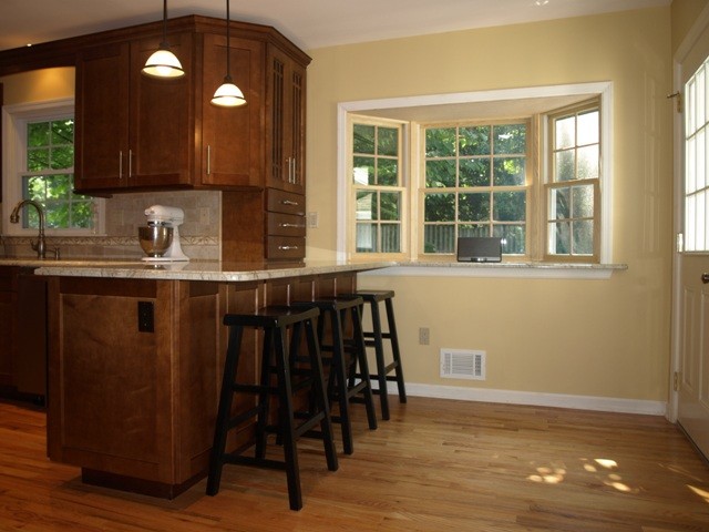 Bild på ett litet amerikanskt kök, med en undermonterad diskho, släta luckor, skåp i mellenmörkt trä, granitbänkskiva, beige stänkskydd, stänkskydd i porslinskakel, rostfria vitvaror, mellanmörkt trägolv och en halv köksö