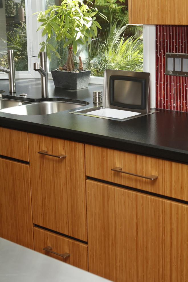 Photo of a small kitchen/diner in San Francisco with a triple-bowl sink, flat-panel cabinets, medium wood cabinets, granite worktops, red splashback, glass tiled splashback, stainless steel appliances and an island.