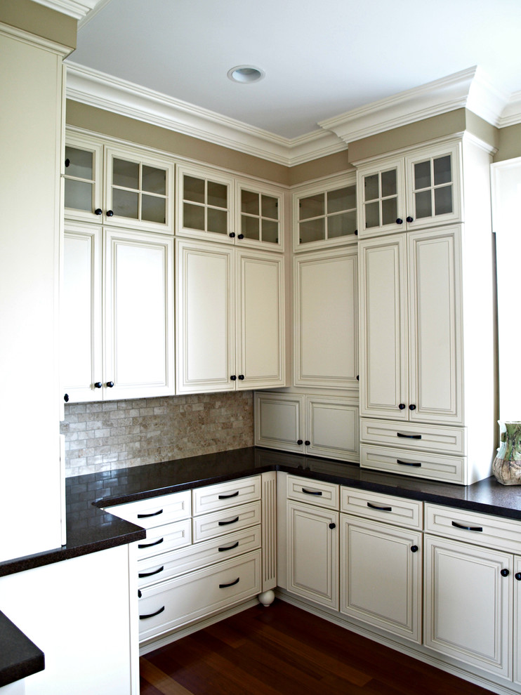 Kitchen pantry - large traditional u-shaped medium tone wood floor kitchen pantry idea in New York with an undermount sink, raised-panel cabinets, beige cabinets, quartz countertops, beige backsplash, stone tile backsplash, stainless steel appliances and an island