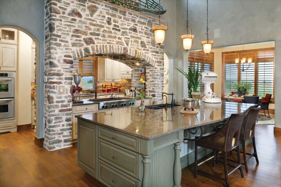 Cette image montre une très grande cuisine parallèle rustique avec un placard avec porte à panneau encastré, un plan de travail en granite et îlot.