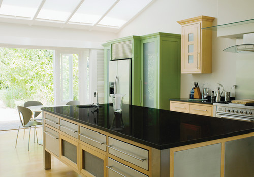 Modern kitchen with black artificial stone countertops on a wood island and green engineered wood cabinets
