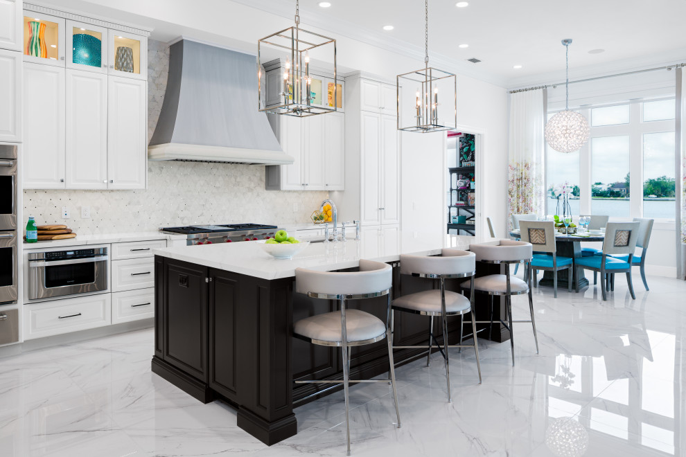 Transitional galley white floor kitchen photo in Tampa with raised-panel cabinets, white cabinets, white backsplash, mosaic tile backsplash, stainless steel appliances, an island and white countertops