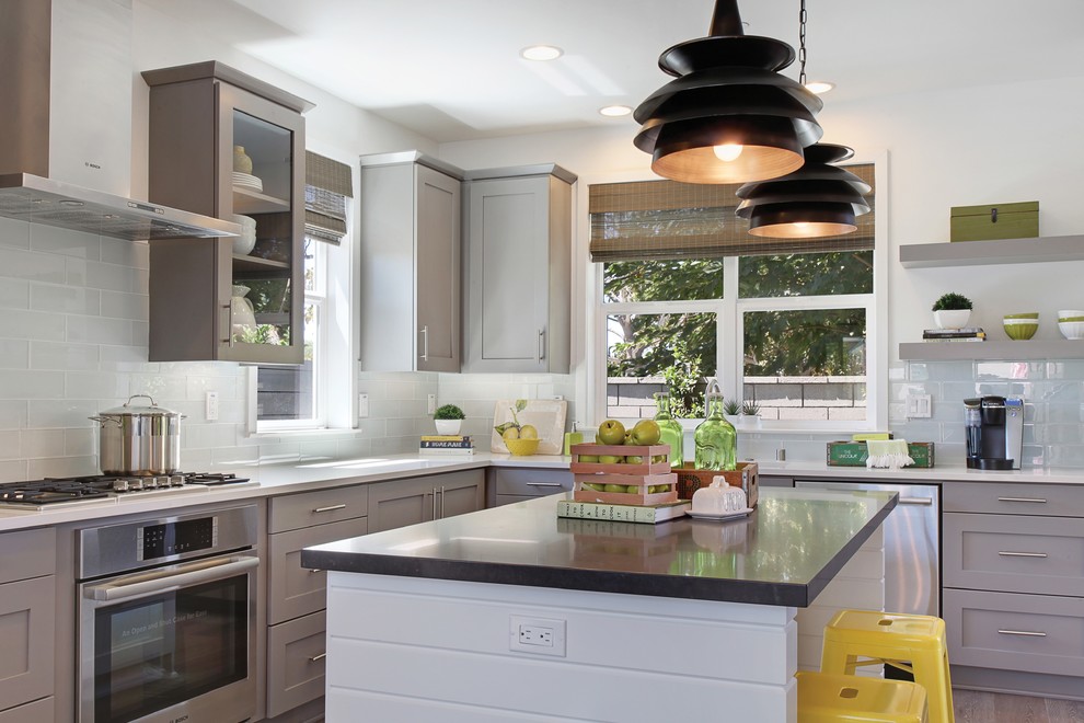 Eat-in kitchen - mid-sized transitional l-shaped medium tone wood floor and brown floor eat-in kitchen idea in Portland with an undermount sink, shaker cabinets, gray cabinets, solid surface countertops, white backsplash, porcelain backsplash, stainless steel appliances and an island