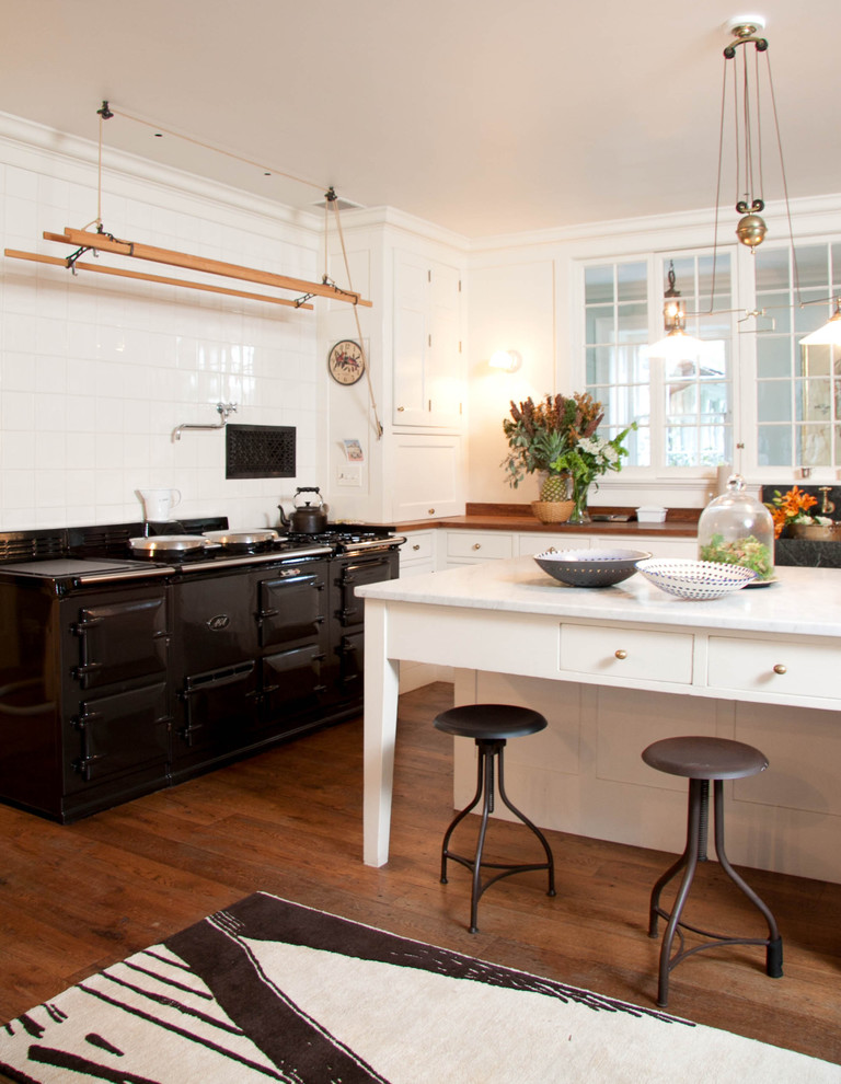 Ejemplo de cocina de estilo de casa de campo con electrodomésticos negros y encimera de mármol