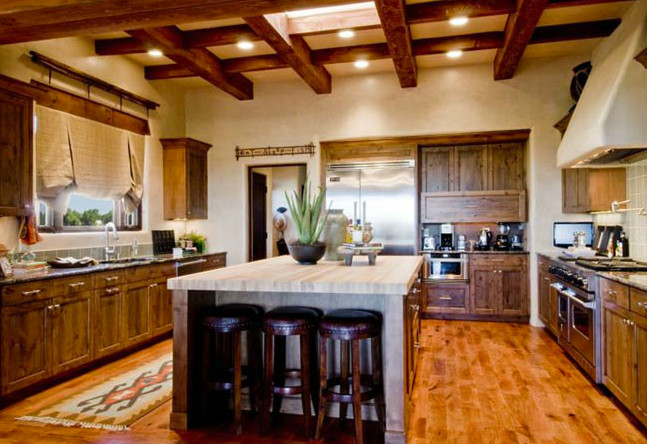 Large rustic u-shaped kitchen in Houston with a built-in sink, raised-panel cabinets, medium wood cabinets, composite countertops, green splashback, stainless steel appliances, medium hardwood flooring and an island.