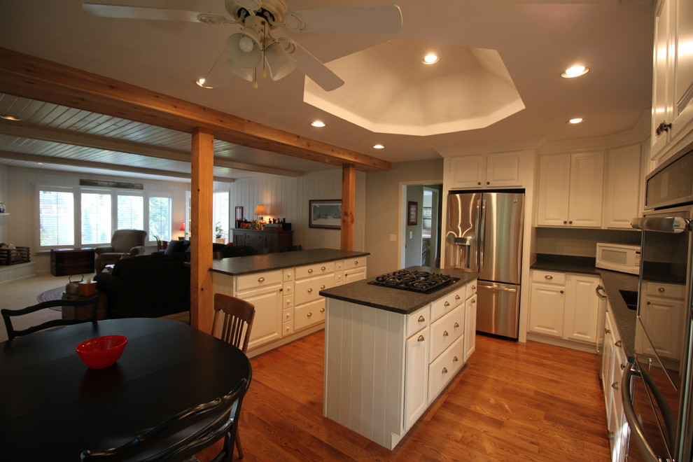Example of a mid-sized transitional medium tone wood floor eat-in kitchen design in Chicago with an undermount sink, raised-panel cabinets, white cabinets, granite countertops, stainless steel appliances and two islands