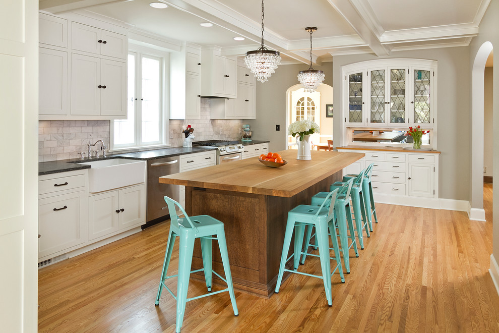 Large elegant single-wall medium tone wood floor enclosed kitchen photo in Minneapolis with a farmhouse sink, shaker cabinets, white cabinets, wood countertops, white backsplash, stone tile backsplash, stainless steel appliances and an island