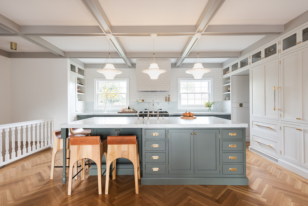 Example of a mid-sized transitional l-shaped medium tone wood floor and brown floor enclosed kitchen design in Salt Lake City with shaker cabinets, white cabinets, an island, white backsplash, subway tile backsplash and stainless steel appliances