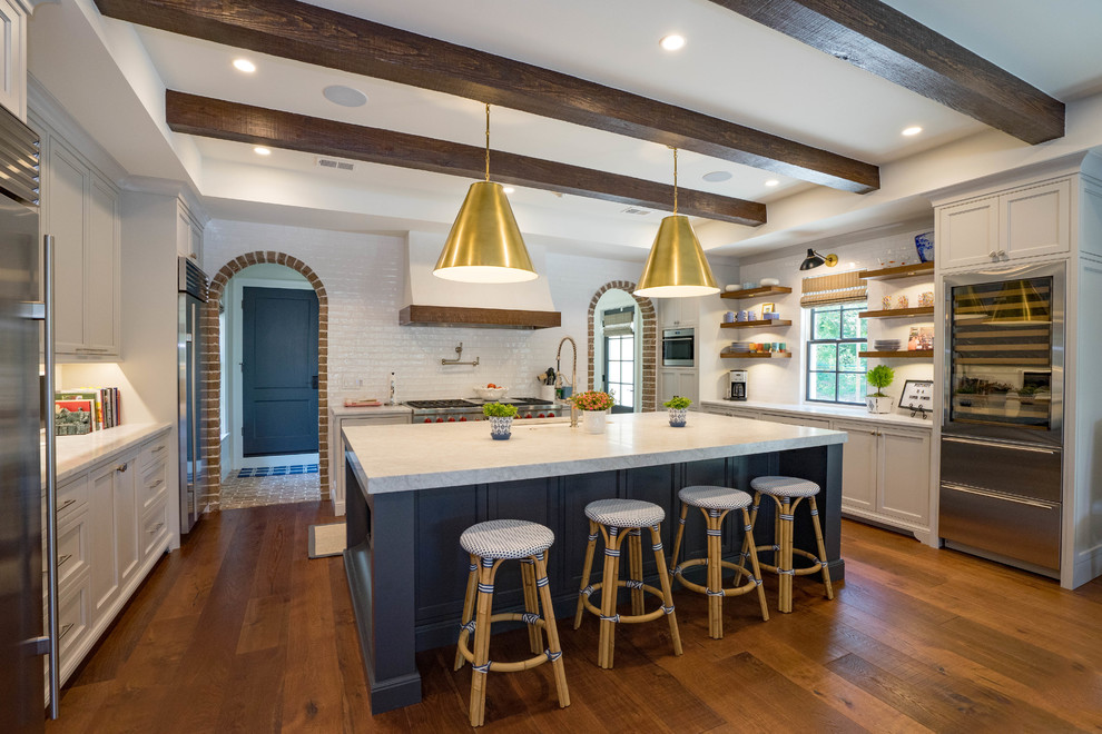 Example of a country dark wood floor and brown floor kitchen design in Other with an undermount sink, beaded inset cabinets, gray cabinets, marble countertops, white backsplash, subway tile backsplash, gray countertops and stainless steel appliances