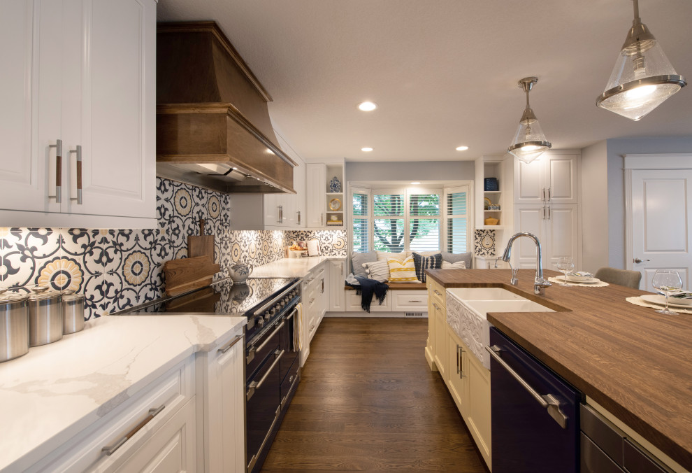 Mid-sized transitional l-shaped dark wood floor enclosed kitchen photo in Denver with a farmhouse sink, raised-panel cabinets, yellow cabinets, wood countertops, multicolored backsplash, porcelain backsplash, colored appliances, an island and brown countertops