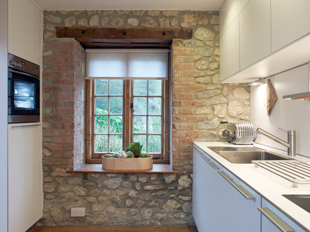 На фото: маленькая отдельная, параллельная кухня в стиле рустика с плоскими фасадами и белыми фасадами без острова для на участке и в саду